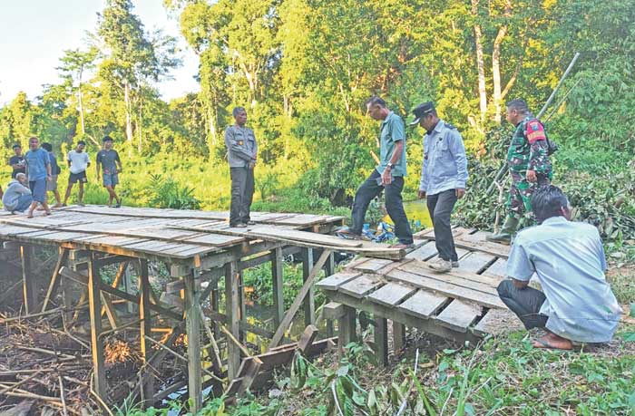 DIPROSES HUKUM: Pihak kepolisian bersama aparatur desa dan kecamatan saat mengecek lokasi Jembatan Ribau yang sengaja dirusak, Rabu (2/7) lalu.