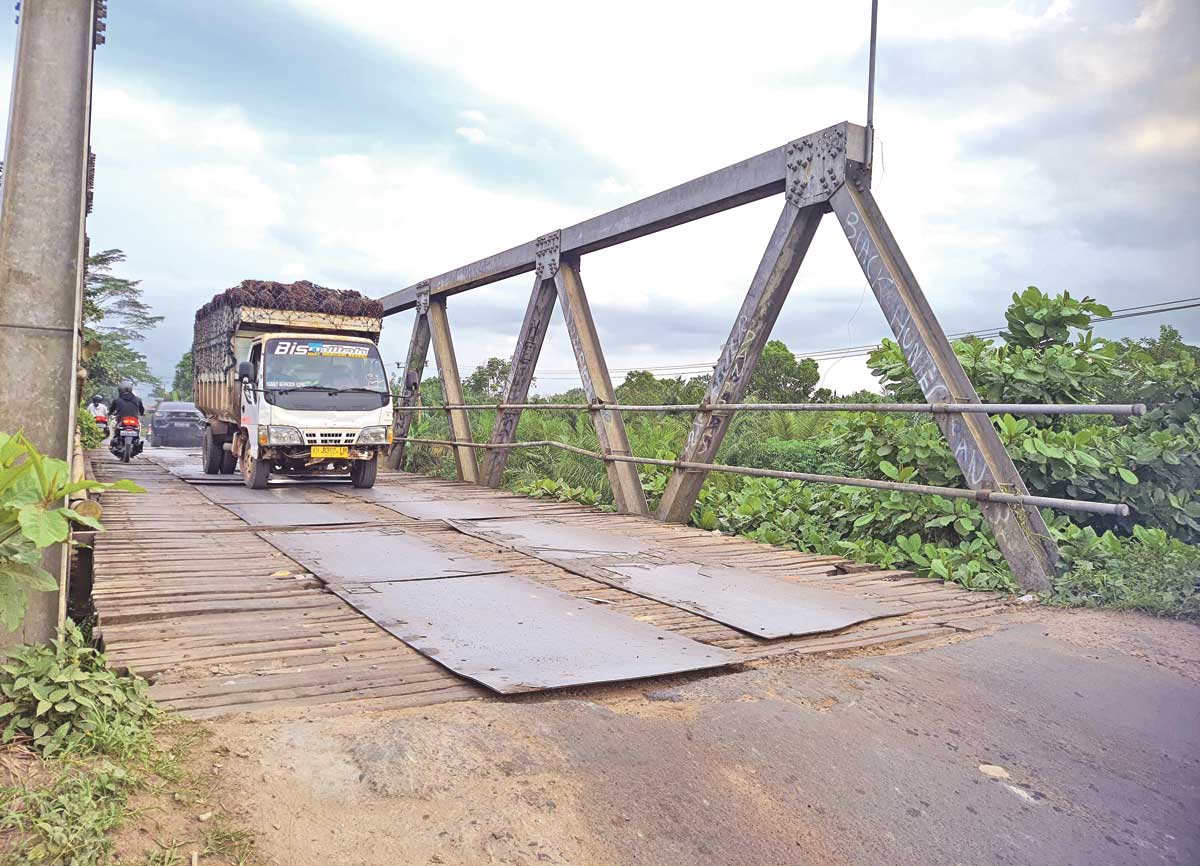 DIHANTAM BEBAN: Sebuah truk penuh muatan tandan buah segar (TBS) kelapa sawit melintas di Jembatan Patah, Jumat (11/7).