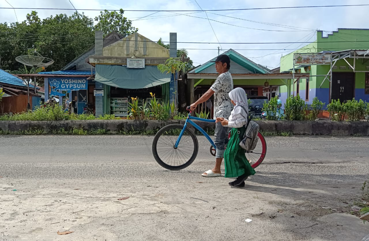 Seorang ayah di Sampit, Kotawaringin Timur, menjemput anaknya pulang sekolah menggunakan sepeda.