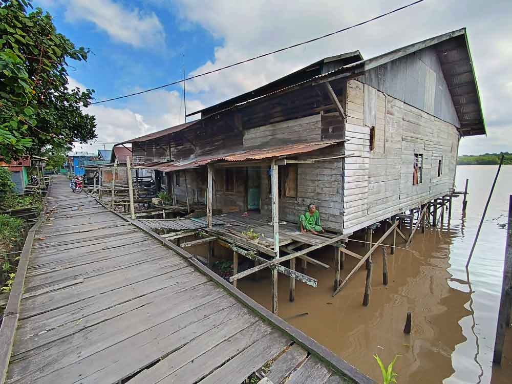 Seorang nenek di permukiman tepi sungai di Kecamatan Mentawa Baru Ketapang, Kabupaten Kotawaringin Timur, asyik memancing di depan sebuah rumah panggung. (Usay Nor Rahmad untuk Radar Sampit)