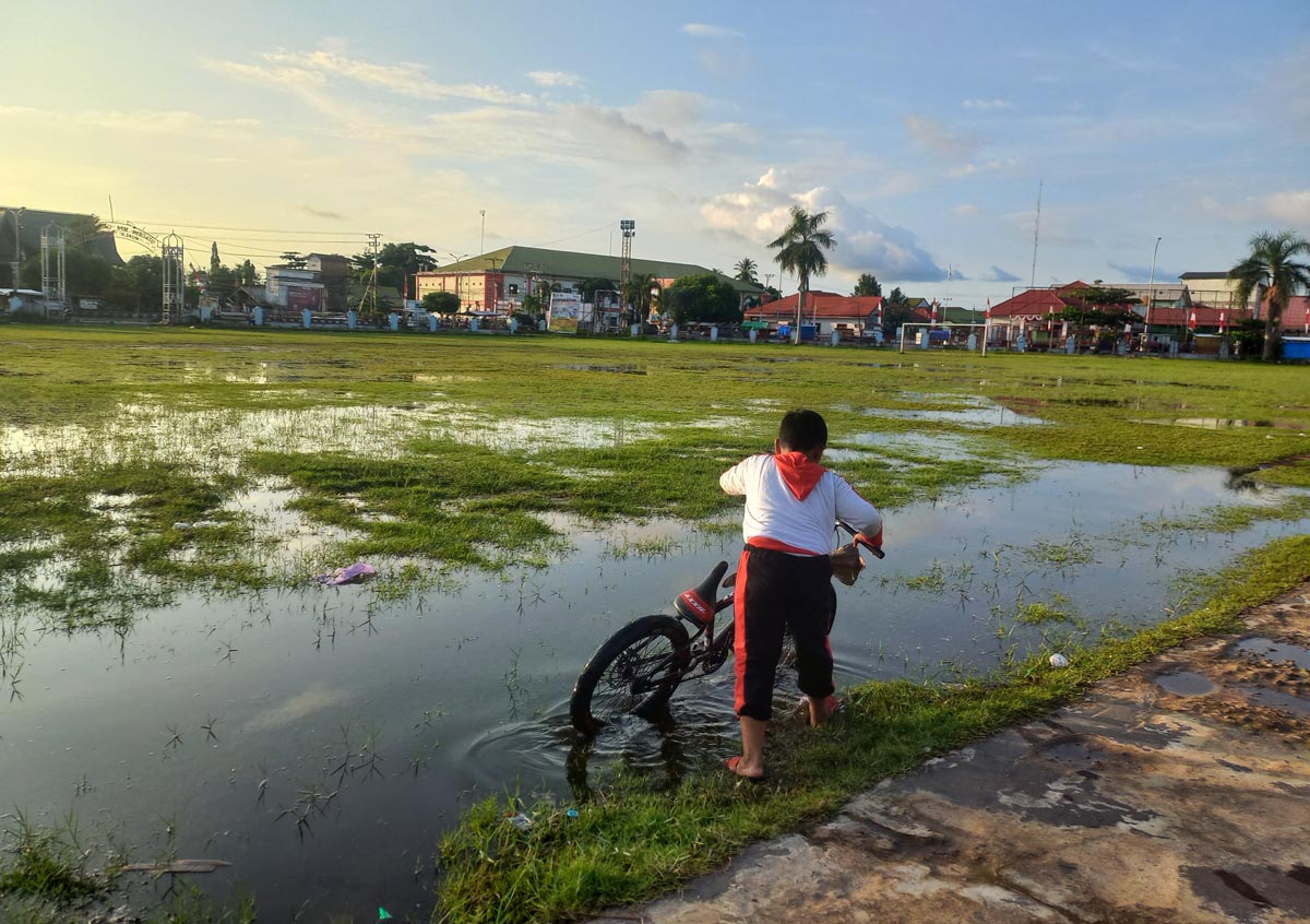 TERENDAM: Seorang anak bermain di lapangan Gagah Lurus Kuala Pembuang yang sedang tergenang air, Senin (4/8).