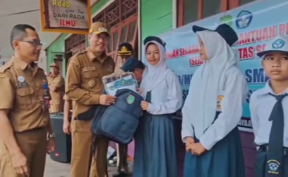 Bupati Sukamara Masduki saat menyerahkan bantuan seragam dan tas sekolah kepada pelajar.