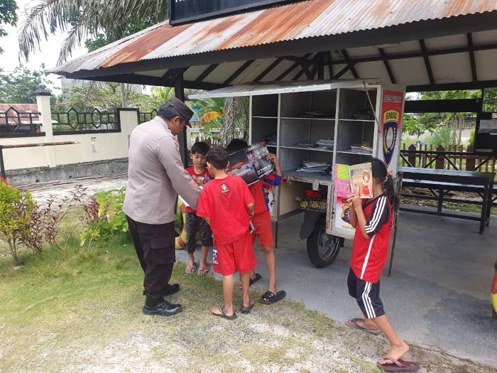 PROGRAM BAJAKA : Bhabinkamtibmas Kelurahan Gaung Baru, Brigadir M. Syifa membagikan buku bacaan kepada anak-anak di halaman Polsek Rakumpit. FOTO: POLSEK RAKUMPIT/RADAR SAMPIT