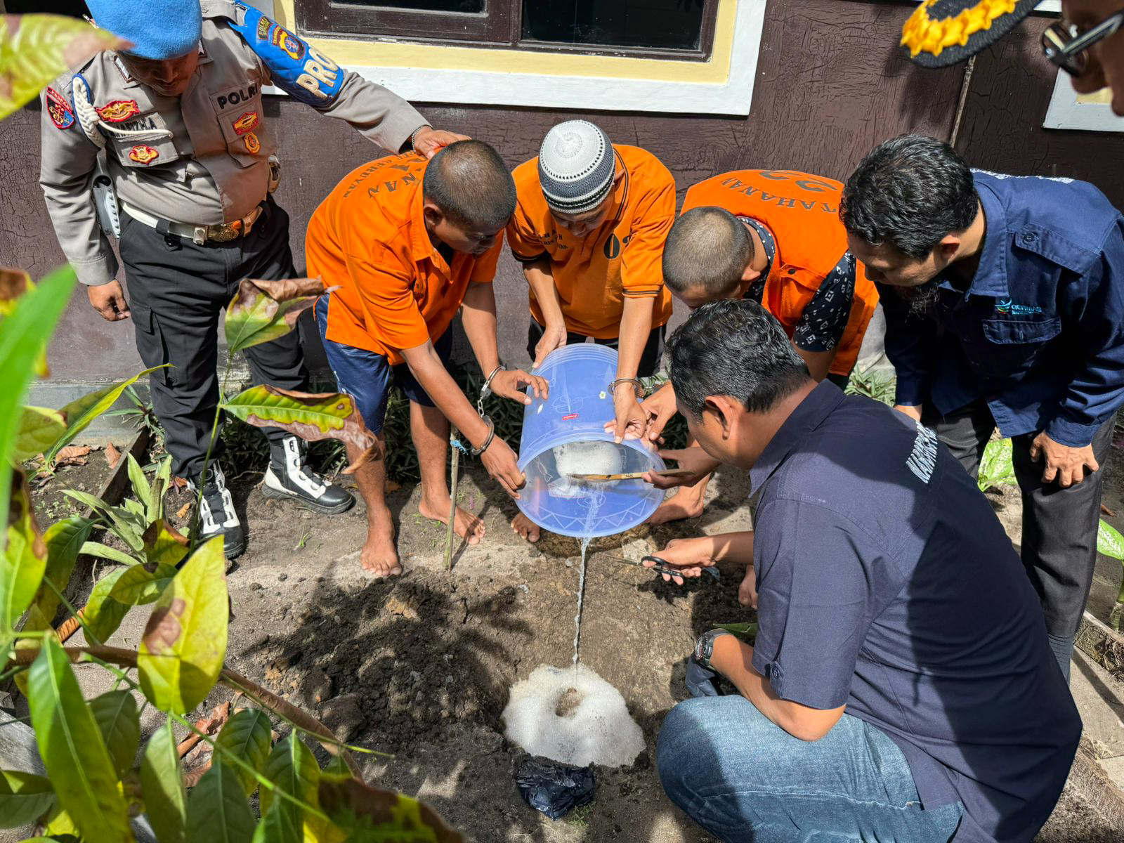 Kaur Binopsnal Satresnarkoba Ipda Dwi Priyono bersama para tersangka membuang cairan barang bukti ke galian tanah, Kamis (21/8).