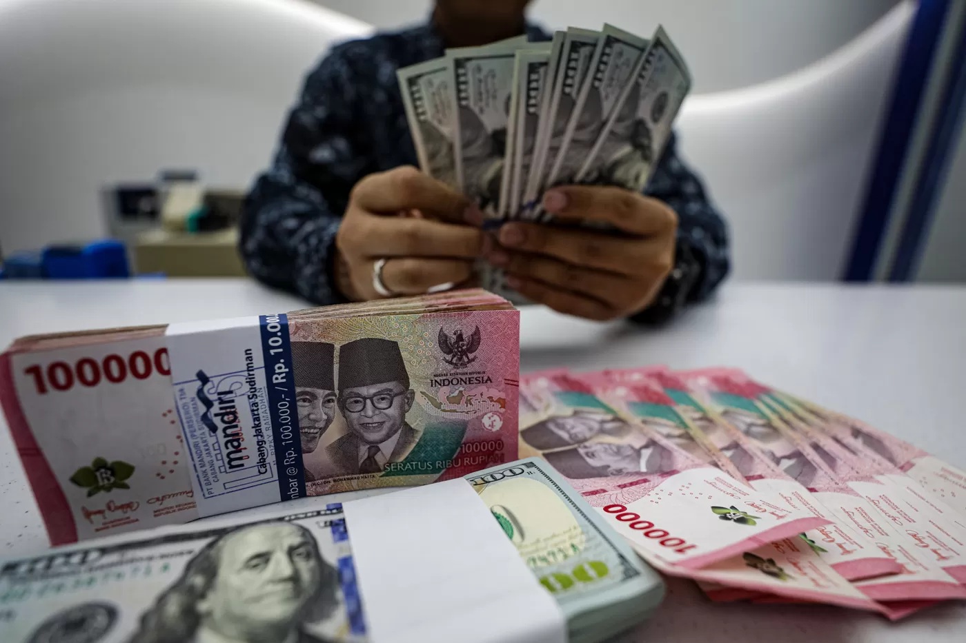 LUSTRASI. Pegawai menunjukkan mata uang Dolar Amerika dan Rupiah di salah satu kantor cabang Bank Mandiri di Jakarta, Selasa (22/7/2025). (Salman Toyibi/Jawa Pos)