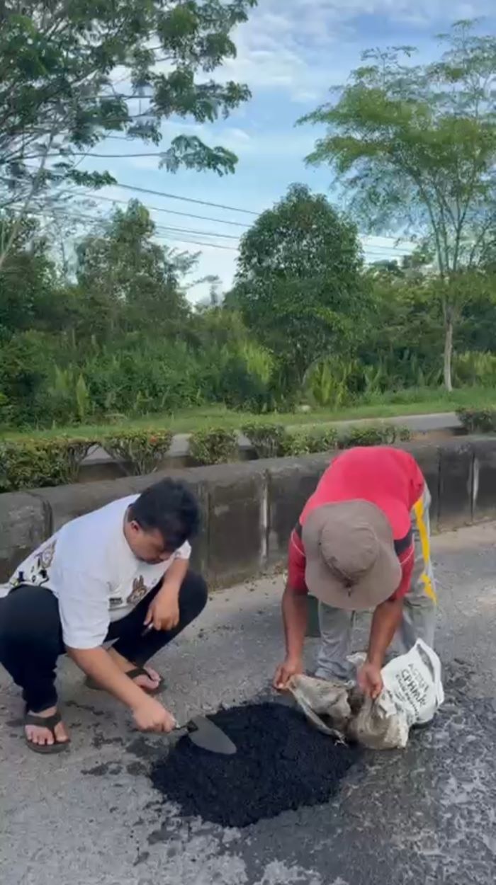 TAMBAL : Bupati Lamandau Rizky Aditya Putra menambal jalan berlubang di dalam kota Nanga Bulik. FOTO: RIA/RADAR SAMPIT