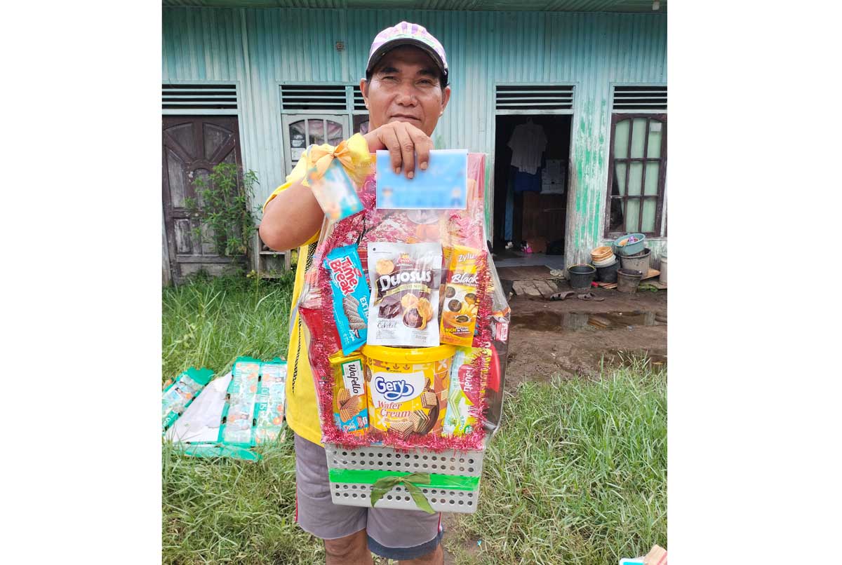 BERJUANG SENDIRI: Anang Mukri di depan barakan tempat tinggalnya saat mendapat bingkisan dari dermawan.