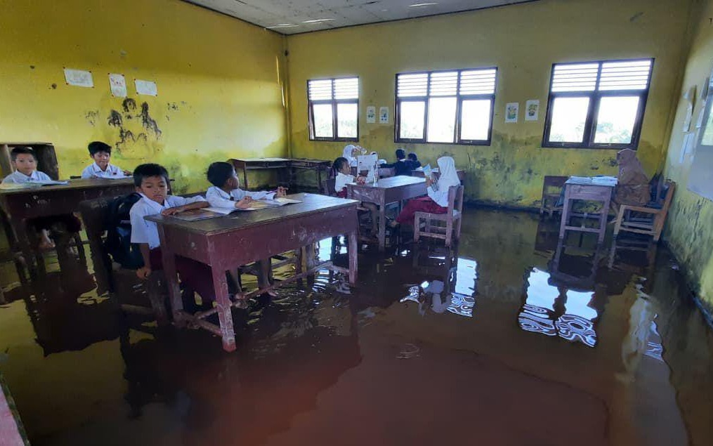 Pelajar SDN Kunjung Lampuyang, tetap belajar di tengah kondisi banjir rob yang merendam sekolah mereka. (Endra Wijaya)