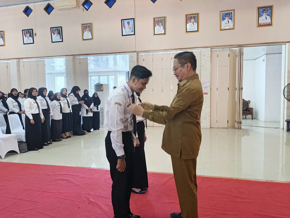 Bupati Sukamara Masduki mengalungkan tanda peserta bagi PPPK yang mengikuti orientasi.