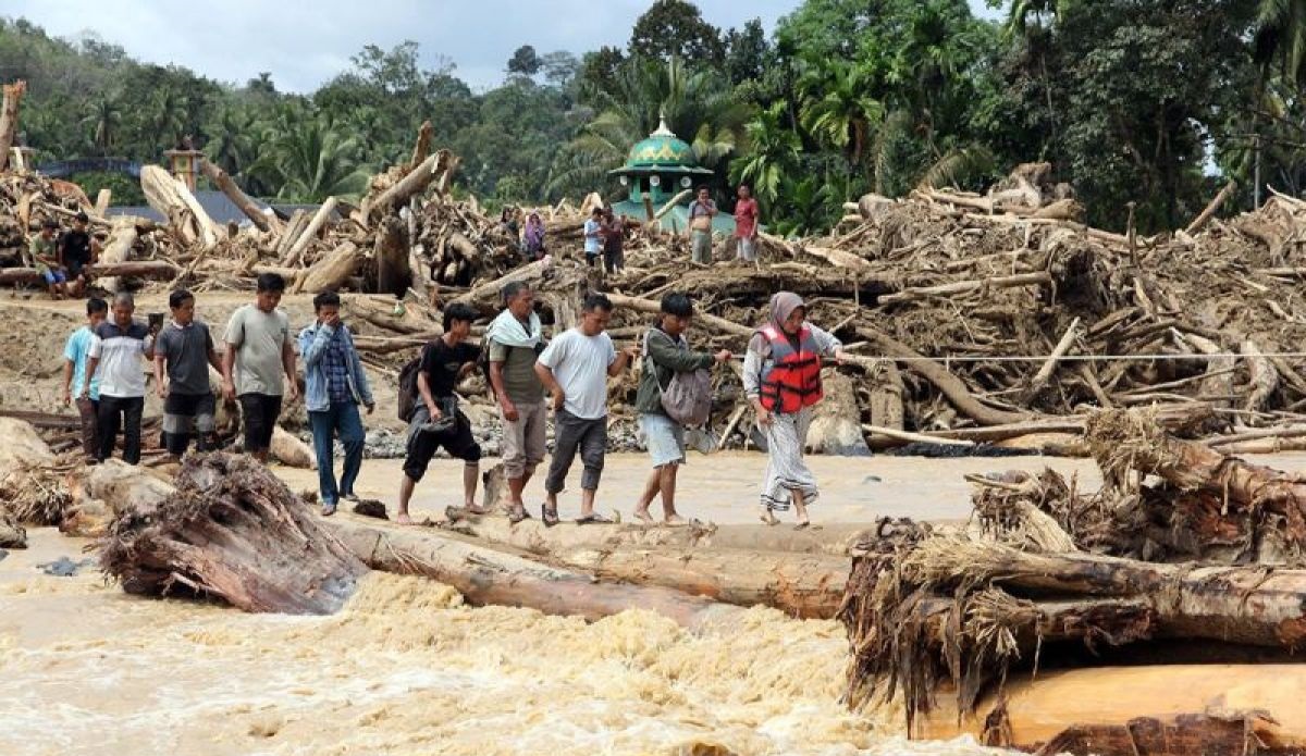 Warga berjalan melintasi sungai dengan jembatan darurat di Desa Aek Garoga, Kecamatan Batang Toru, Kabupaten Tapanuli Selatan, Sumatera Utara, Sabtu (29/11).