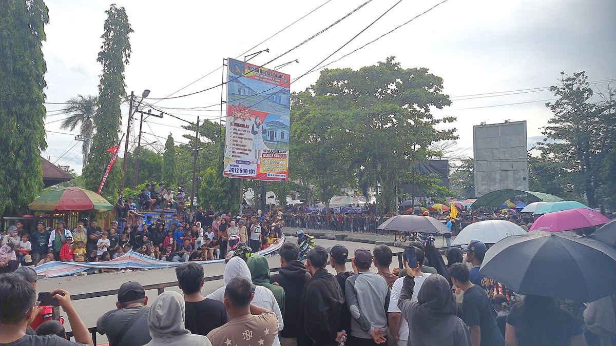 PENONTON : Ribuan penonton nekat menerobos terpal pembatas, menyaksikan pertandingan open race di jalur lintasan hingga menutupi separuh badan Jalan Yos Sudarso, Taman Kota Sampir, Minggu (14/12).&nbsp;