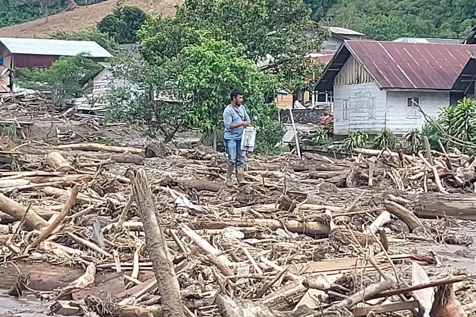 Warga Takengon berdiri di antara kayu-kayu yang terbawa banjir dan longsor. (Jurnalisa untuk JawaPos.com)