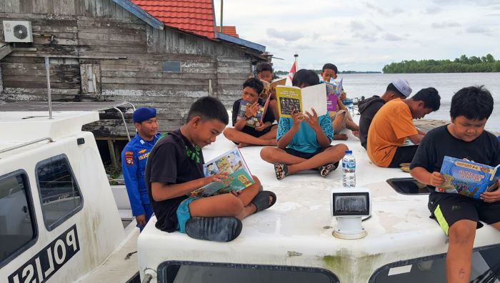 LITERASI: Anak-anak serta warga yang tinggal di sekitar dermaga dan permukiman tepian Sungai Seruyan membaca buku yang disediakan di Perputakaan Terapung. FOTO: RIFANI/RADAR SAMPIT