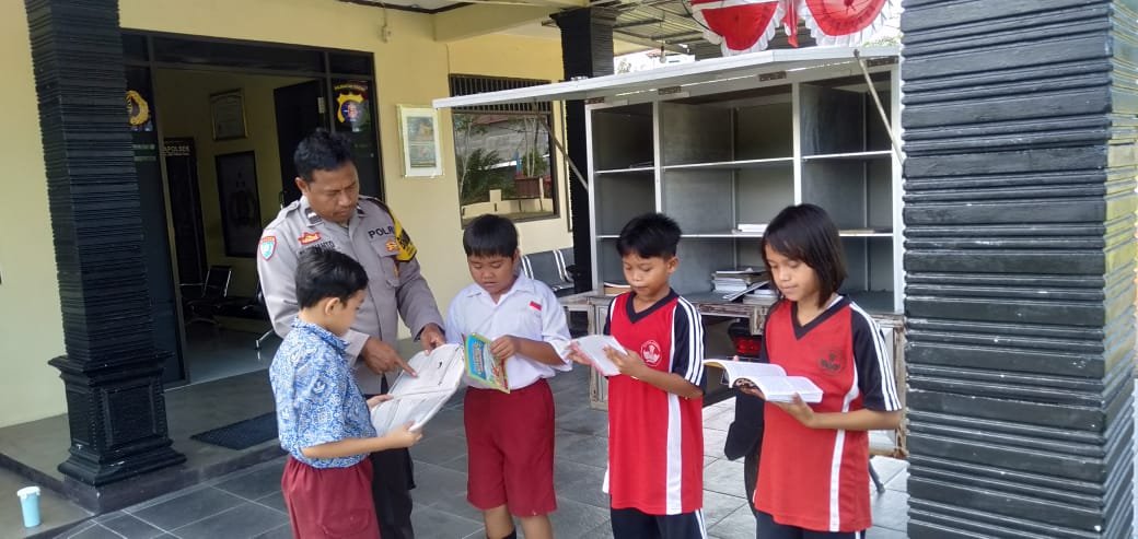 Anggota Polsek Rakumpit saat membagikan buku bacaaan kepada anak-anak melalui kegiatan Bhayangkara Penjaga Aksara, Sabtu (10/1).