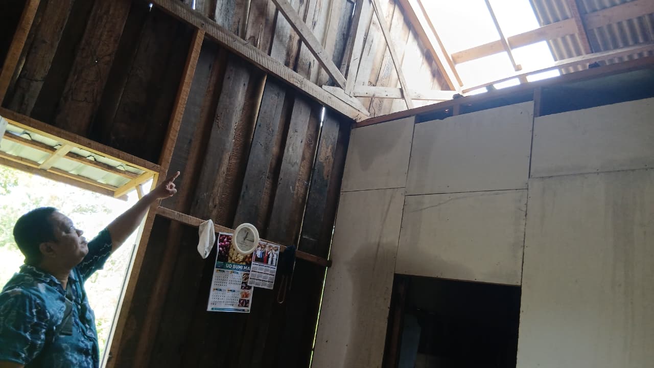 Salah seorang petugas menunjukkan atap rumah warga yang rusak akibat angin kencang yang terjadi di Sampit, Kotawaringin Timur belum lama ini. (TRC BPBD Kotim)