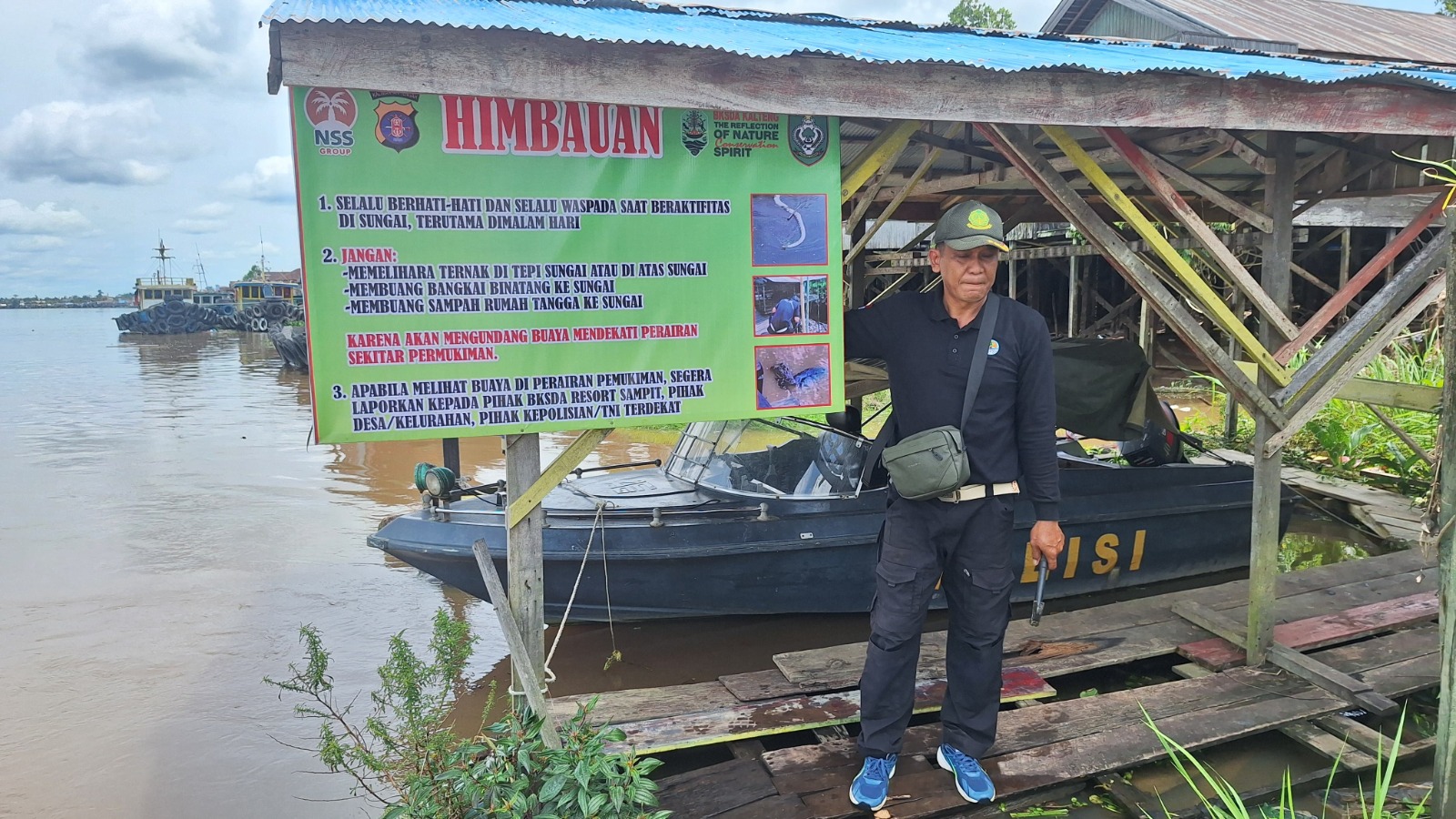 Kepala BKSDA Resort Sampit Muriansyah saat memasang spanduk di Kelurahan Kota Besi Hulu lokasi yang kerap terjadi kemunculan buaya besar. (BKSDA Resort Sampit)