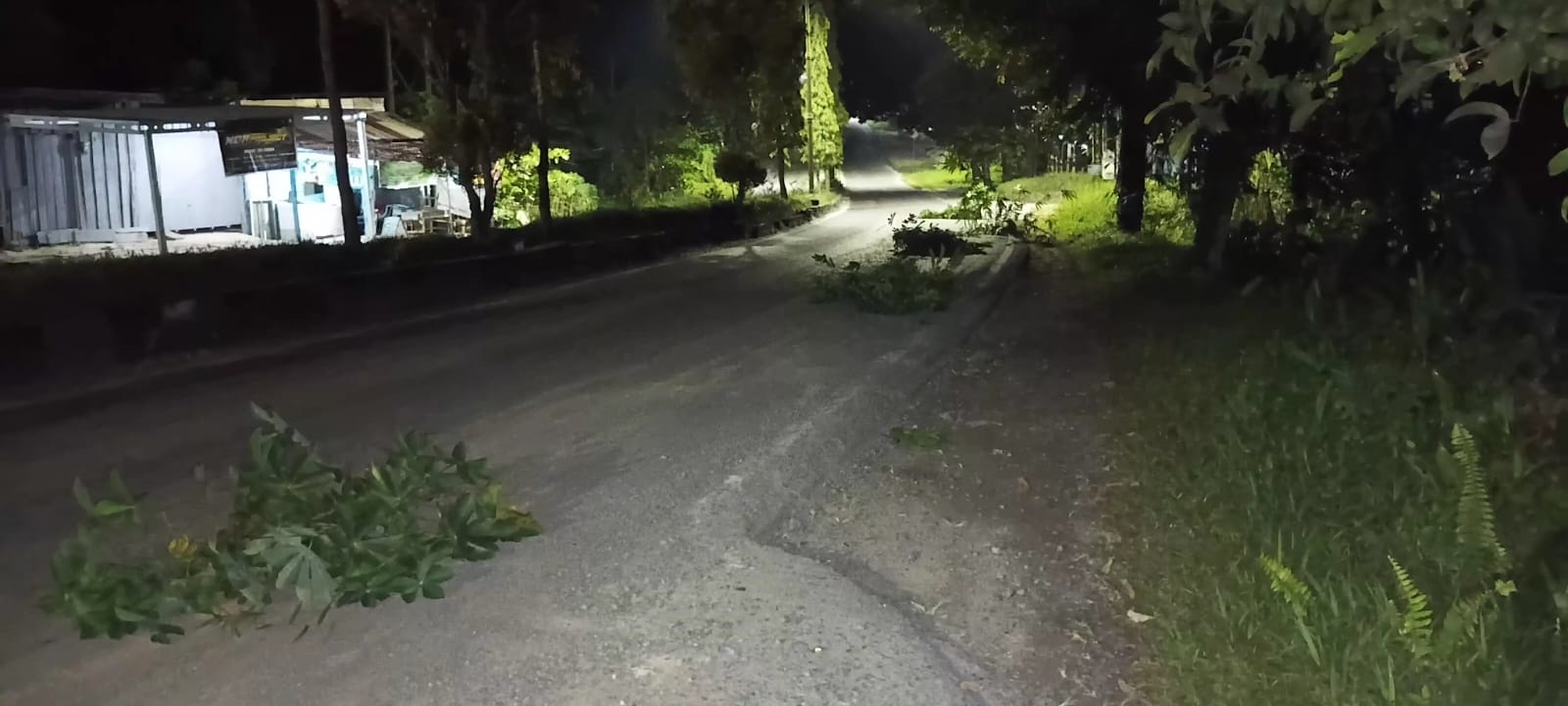 Warga meletakan daun-daun di atas jalan yang terdapat kerikil dan pasir untuk meminimalkan resiko kecelakaan di Jalan Ahmad Yani, Natai Pelingkau, Kelurahan Baru, Minggu (22/2) dini hari.