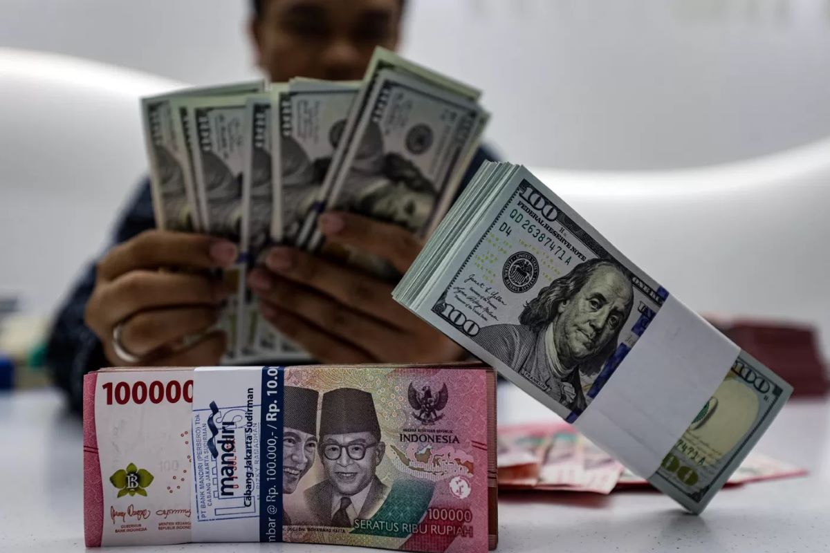 Pegawai bank menunjukan mata uang Dolar Amerika dan Rupiah