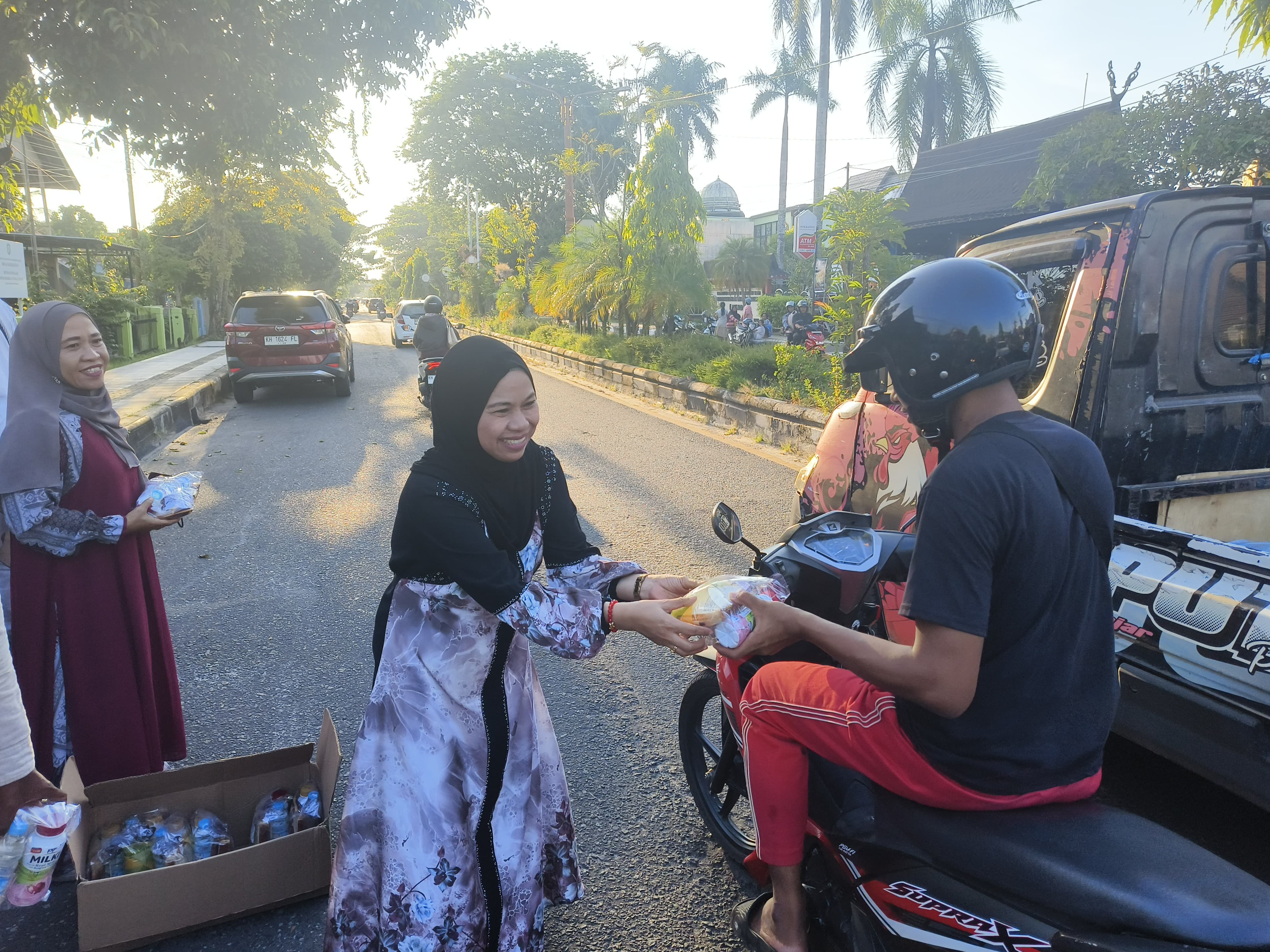 Ketua PWI Kotim, Siti Fauziah, saat membagikan takjil kepada pengendara yang melintas.  (Akbar/Radar Sampit)