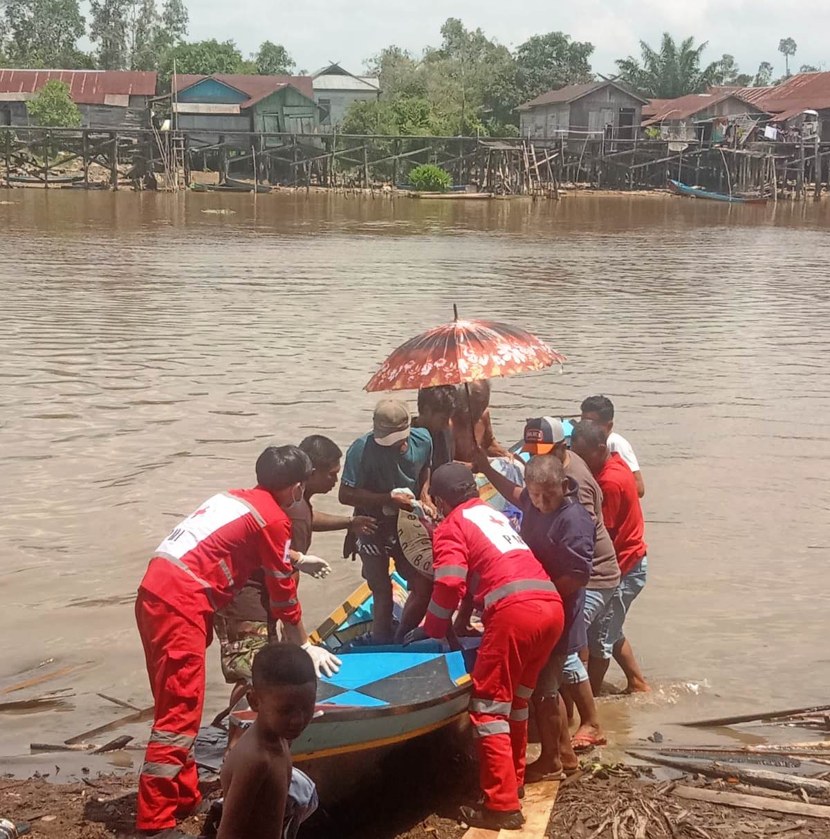 Petugas PMI Kobar dan warga saat mengangkat warga yang sakit keras dari Kelurahan Raja Seberang menuju mobil ambulans di Kelurahan Baru dengan menyeberang sungai Arut, Minggu (29/3).