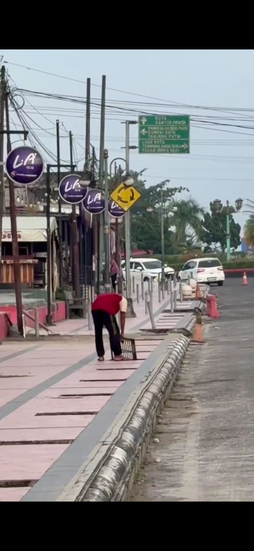 Pria yang diduga ODGJ melepas besi penutup trotoar dan membuangnya ke parit.   