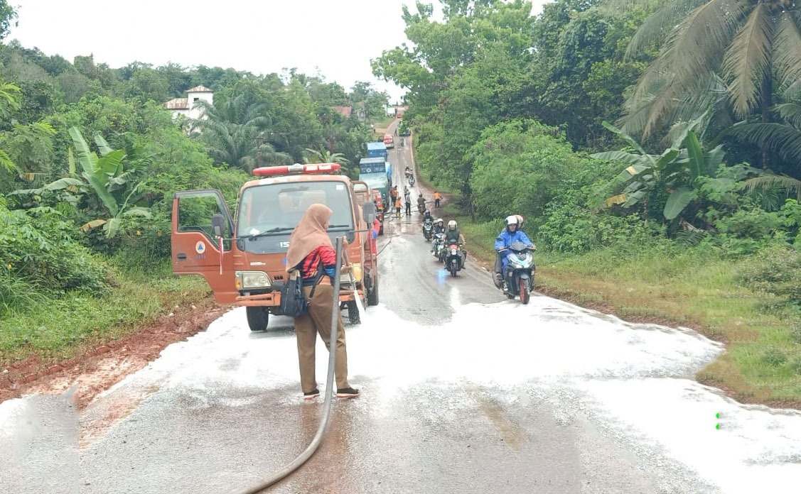 Petugas BPBD Kotim menyiram jalan yang tercemar CPO menggunakan air bercampur zat kimia tertentu agar segera dapat dilalui oleh kendaraan. (BPBD Kotim)