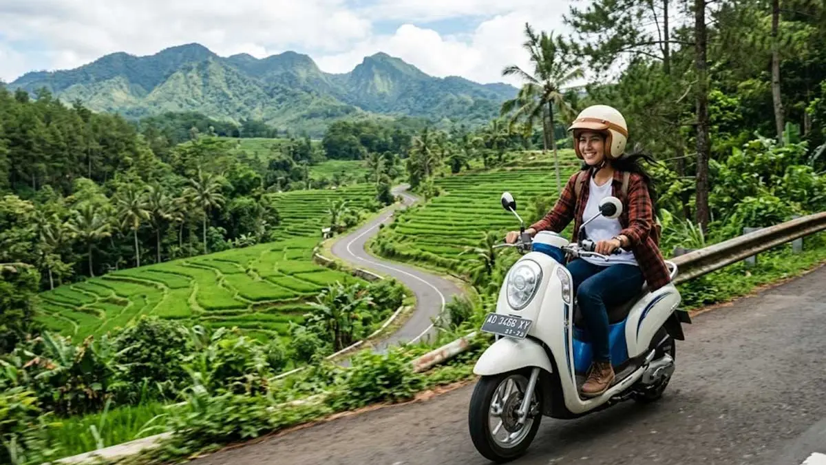 Seorang wanita mengendarai motor matic di daerah pegunungan.