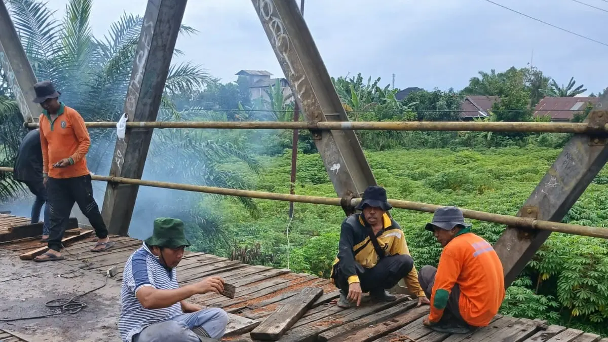 PERBAIKAN: Para pekerja sedang melakukan perbaikan jembatan patah secara tambal sulam. (Warga/Radar Sampit)