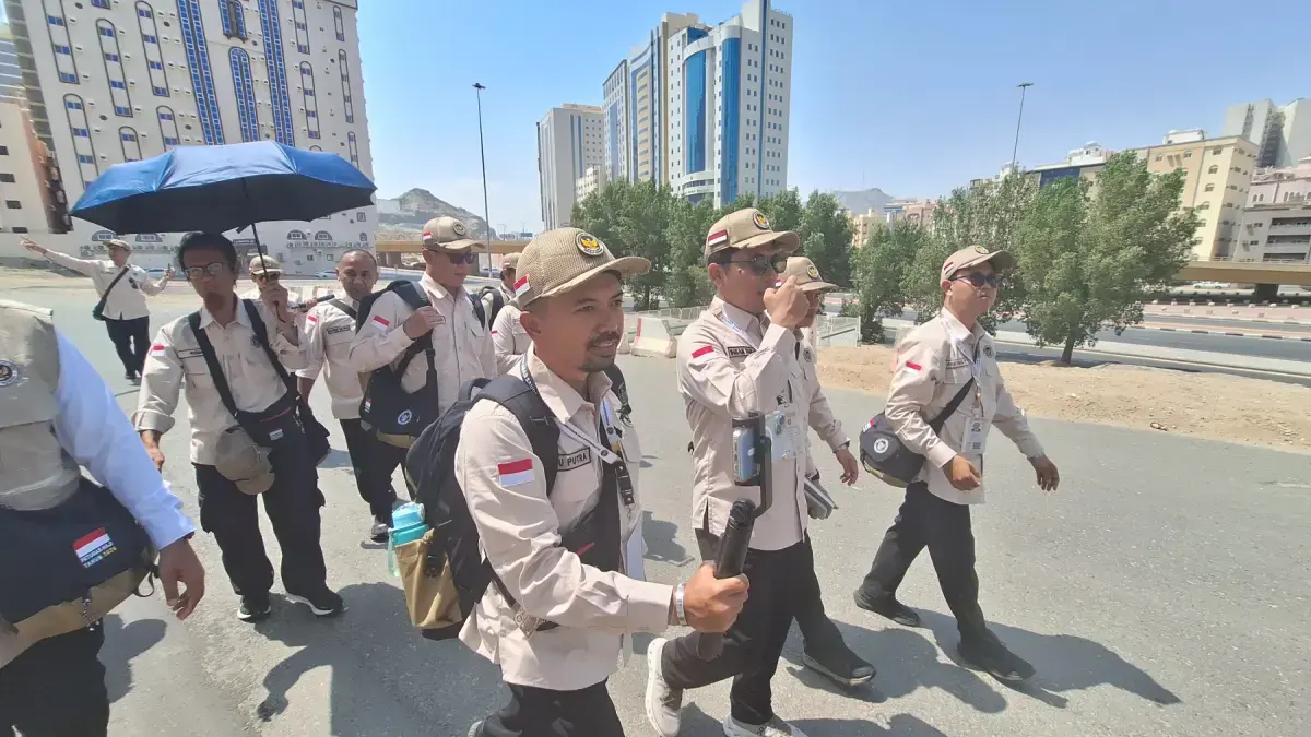 Petugas haji mengenakan payung saat berada di luar ruangan di Makkah. Suhu udara di Tanah Suci semakin meningkat menjelang puncak musim haji, karena berteptan dengan awal musim panas. (Media Center Haji 2026)