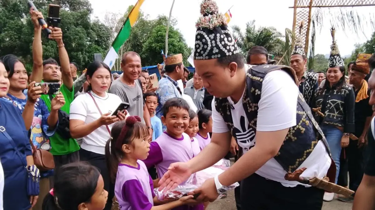 Bupati Lamandau Rizky Aditya Putra menyerahkan seragam gratis untuk murid baru SD. (RIA/RADAR SAMPIT)