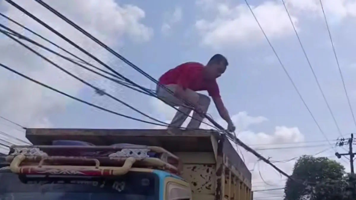 Sopir truk terpaksa turun tangan untuk membenahi kabel agar tak tersangkut. (Warga/Radar Sampit)&nbsp;