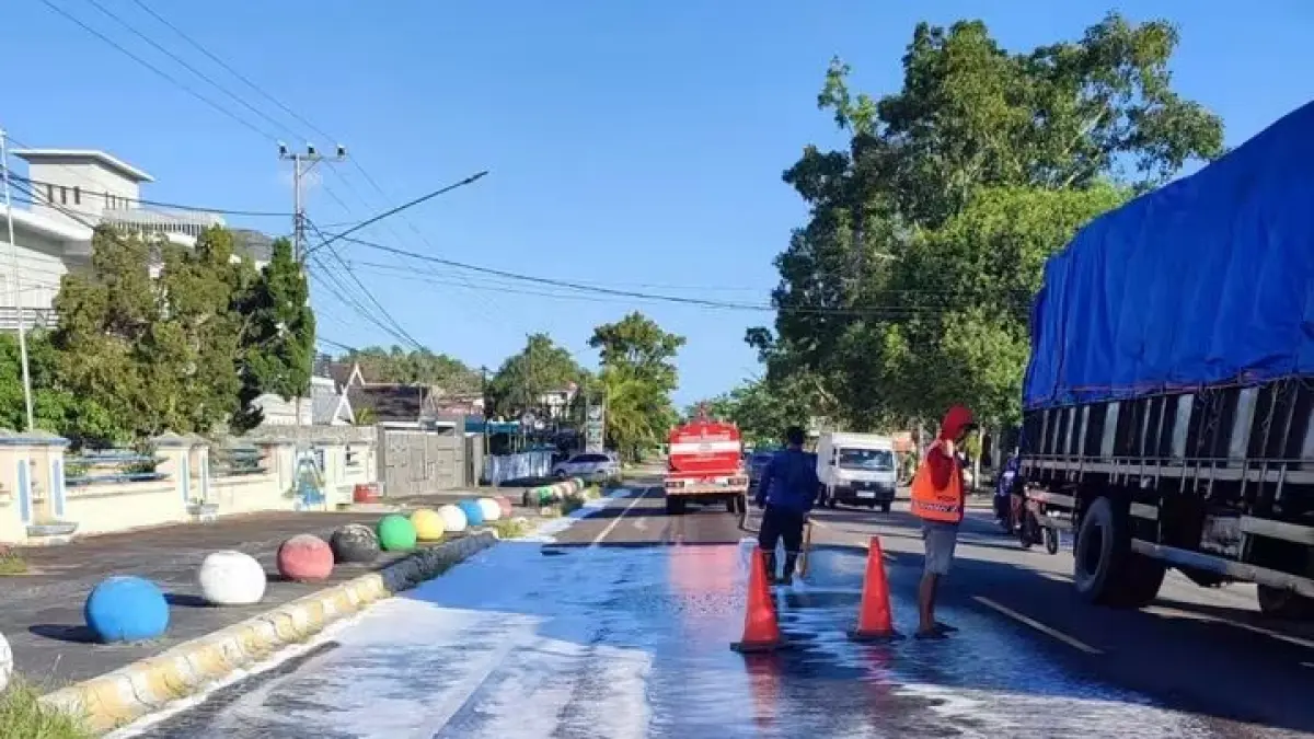 PEMBERSIHAN: Personel Damkar Kobar melakukan pembersihan tumpahan solar di ruas jalan Pasir Panjang, belum lama ini. (Damkar/Radar Sampit)