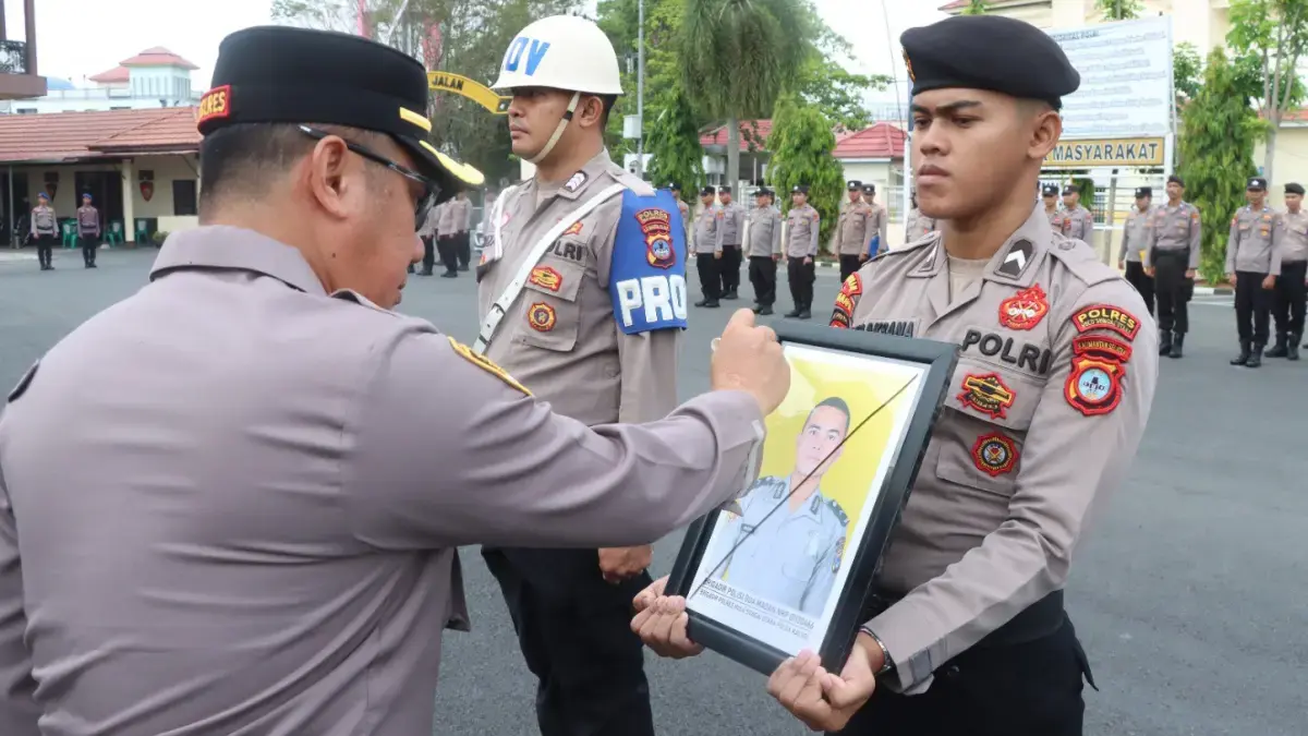 DIPECAT: Kapolres HSU AKBP Agus Nuryanto menyilang tanda X pada foto anggota Polres HSU yang di PTDH di halaman Polres HSU. (radar banjarmasin)