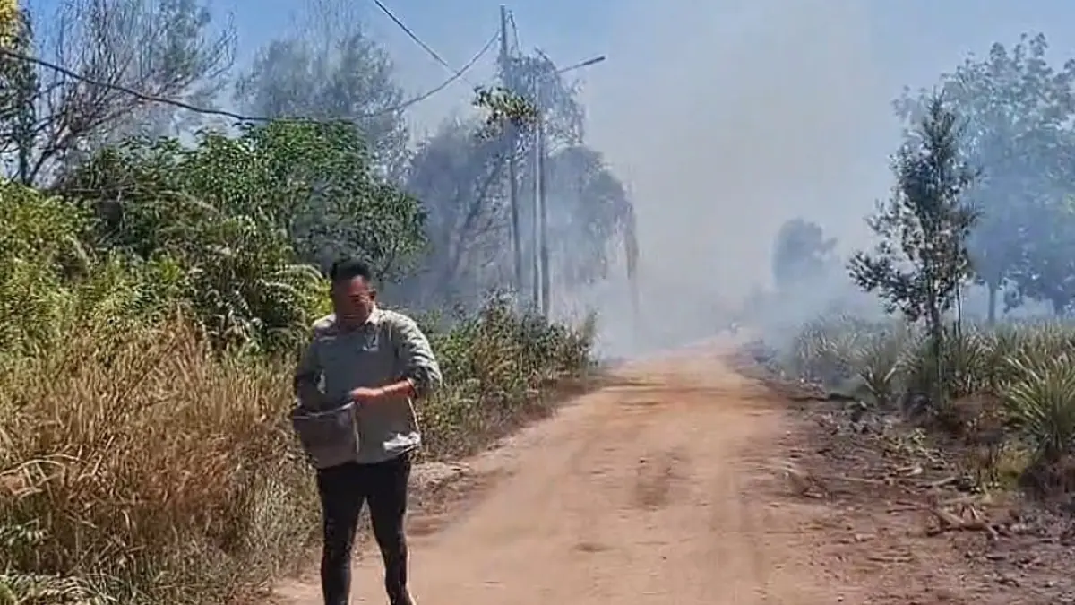 Ketua RT di Kompleks Graha Pramuka Sampit Januar tampak berlari membawa ember untuk memadamkan api yang membakar lahan di tepi jalan poros menuju kompleks tersebut. (Dian/Radar Sampit)