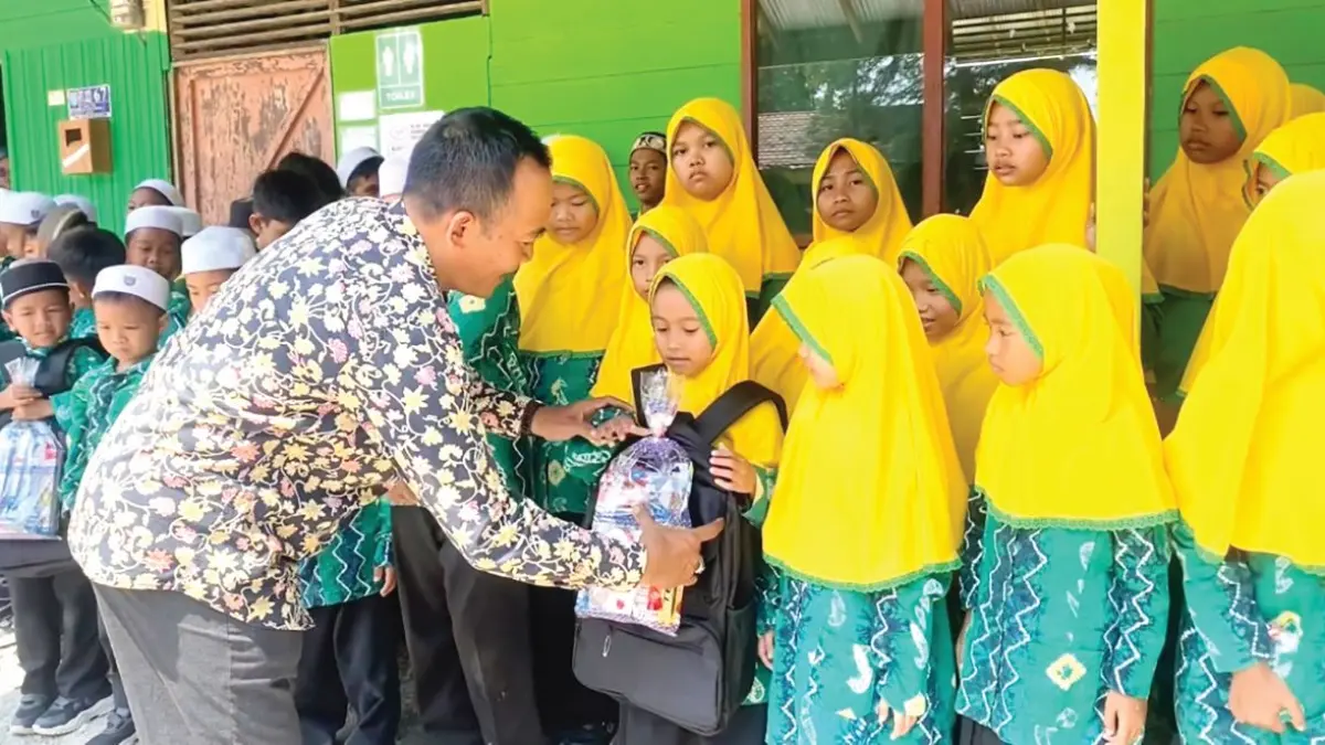 Kepala MI Nurul Islam Gambut, H. Supiyannor, S.Ag., M.A., saat membagikan paket bantuan YBM kepada para siswanya.