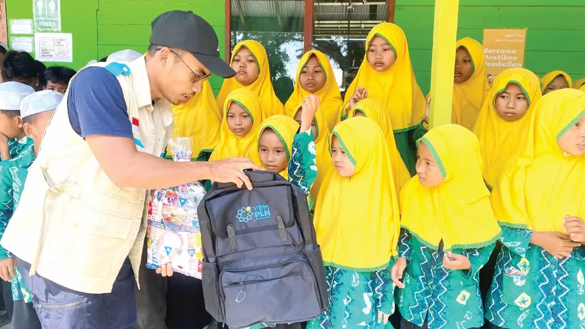 Petugas YBM PLN UID Kalselteng saat membagikan paket bantuan Tas dan Peralatan ATK untuk siswa siswi di MI Nurul Islam Gambut.