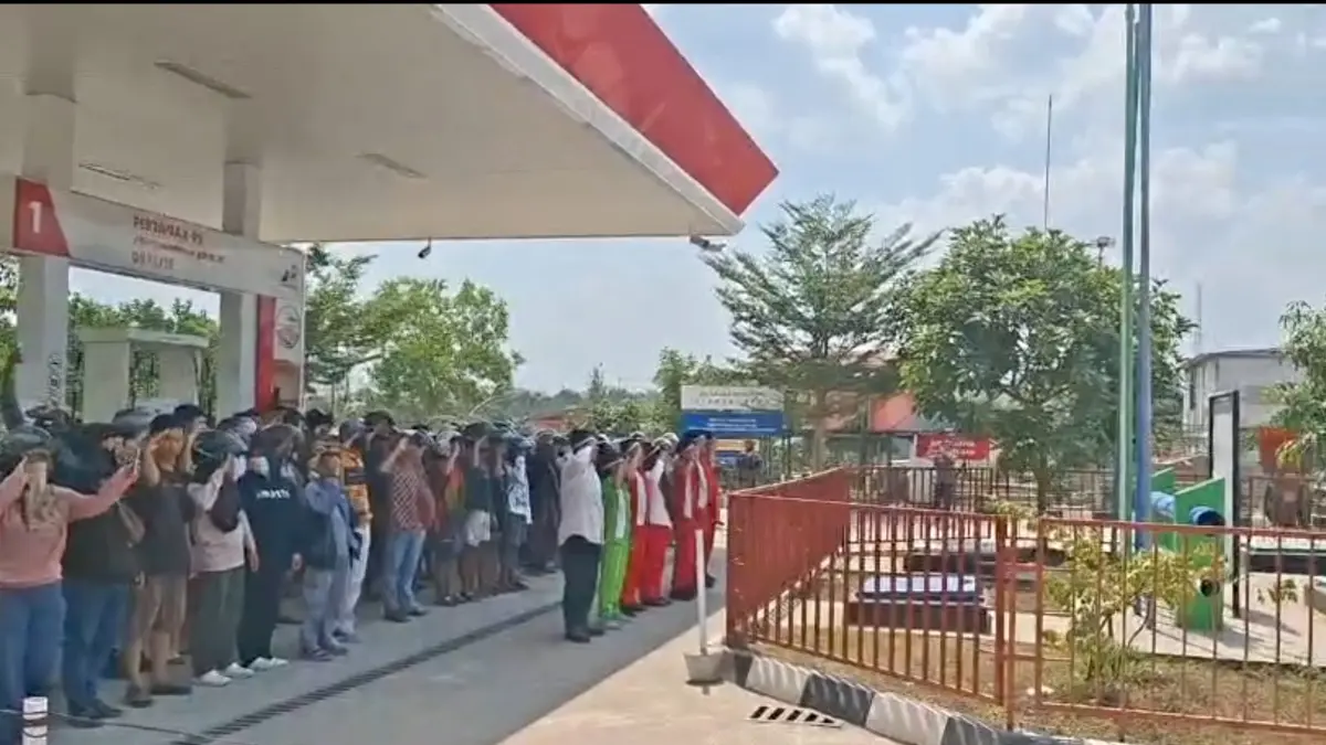 Puluhan warga dan pelangsir yang sejak pagi sudah berada di lokasi karena SPBU belum beroperasi, tiba-tiba menghentikan seluruh aktivitas mereka saat detik-detik penghormatan bendera.
