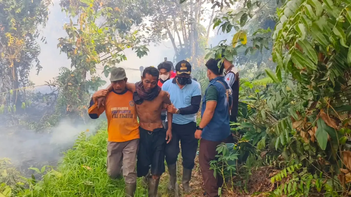Camat Mentawa Baru Ketapang, Irpansyah, saat membantu evakuasi warga yang terjebak akibat kebakaran lahan di Desa Pelangsian.  (Akbar/Radar Sampit)
