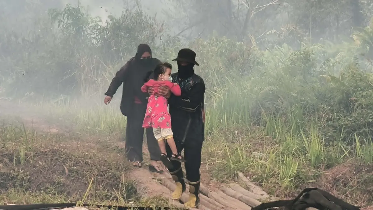 Seorang anak ketika dievakuasi seorang relawan untuk dibawa menjauh dari lokasi kebakaran lahan, yang mendekati pemukiman warga di Jalan Pasendang Ujung, Palangka Raya, Rabu (2/9).(dodi/radarsampit)
