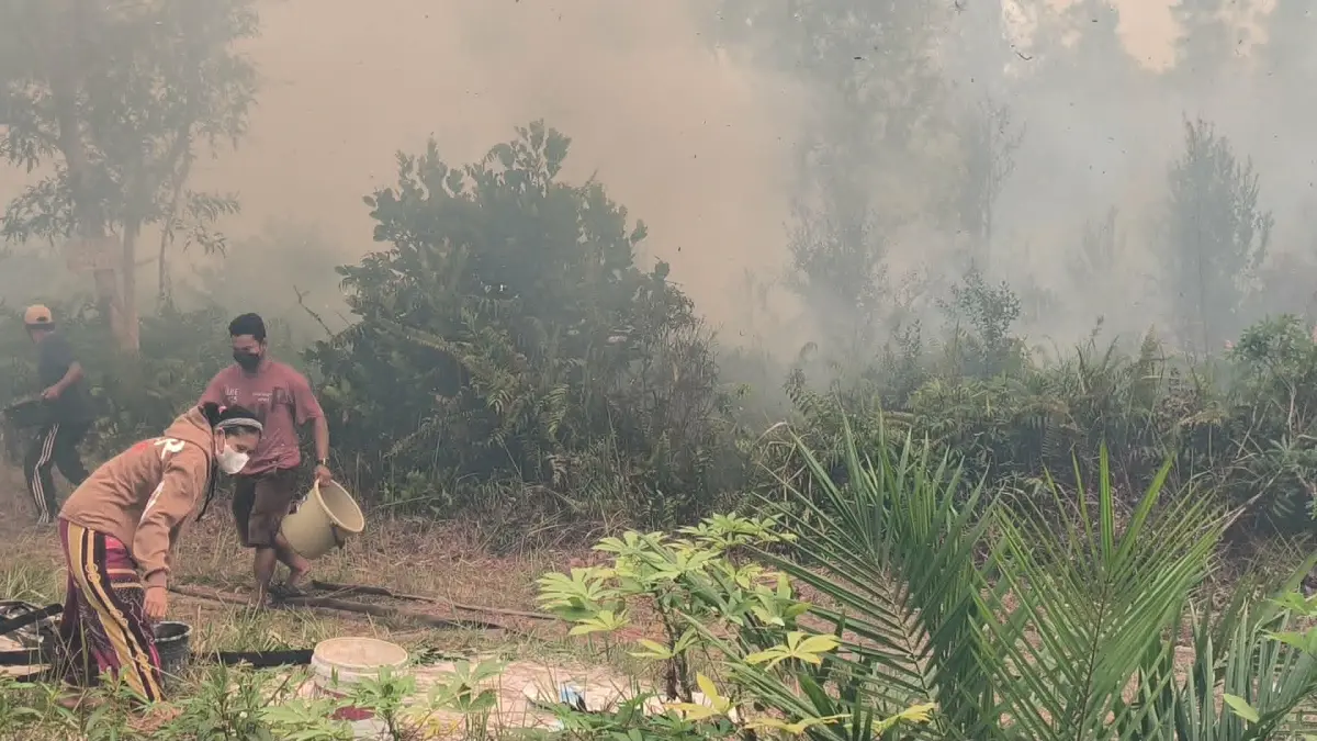 Sejumlah warga ketika turut memadamkan kebakaran lahan yang mendekati areal perumahan, dengan peralatan seadanya.(dok.radarsampit)