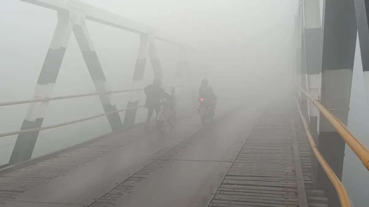 Kabut asap tebal menyelimuti Sampit, Kotawaringin Timur, pengendara harus mengurangi kecepatan karena jarak  pandang yang terbatas dan berbahaya bagi keselamatan berkendara. Tampak pengendara terpaksa turun menuntun sepedanya ketika melewati Jembatan Jalan Kapten Mulyono Sampit, Jumat (2/10/2026). (Usay Nor Rahmad/Radar Sampit)
