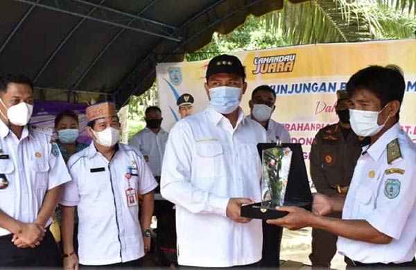 DESA WISATA: Bupati Lamandau Hendra Lesamana saay menyerahkan Piagam dan Plakat Desa Wisata Pesona Indonesia pada Kepala Desa Benakitan. (ISTIMEWA/RADAR SAMPIT)