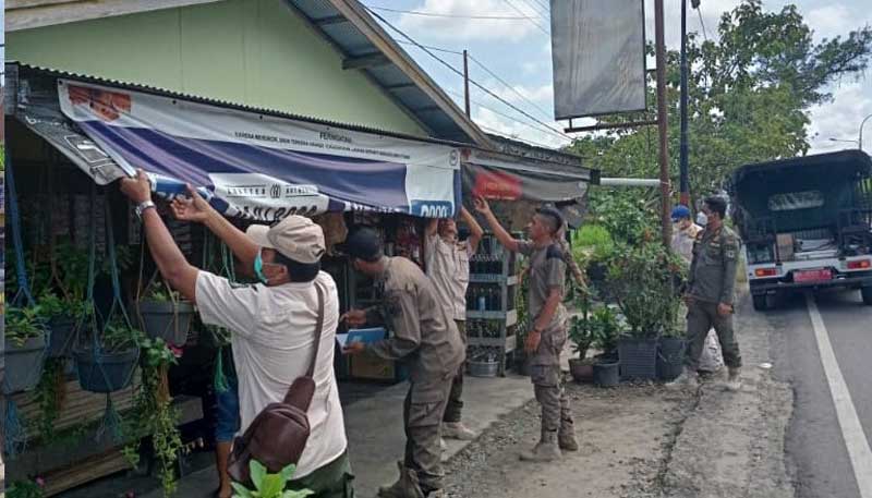 PENERTIBAN: Personil Pol PP Kapus saat melepas label, iklan rokok di salah satu warung dan toko. (ALEXANDER/RADAR SAMPIT)