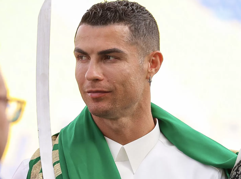 Cristiano Ronaldo dengan gamis putih dan sorban hijau memegang pedang. (x/@Cristiano)