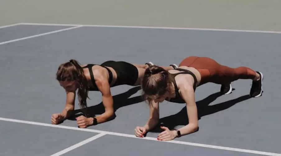 Dua orang yang sedang melakukan gerakan calisthenics, yakni plank (Dok. Pexels)
