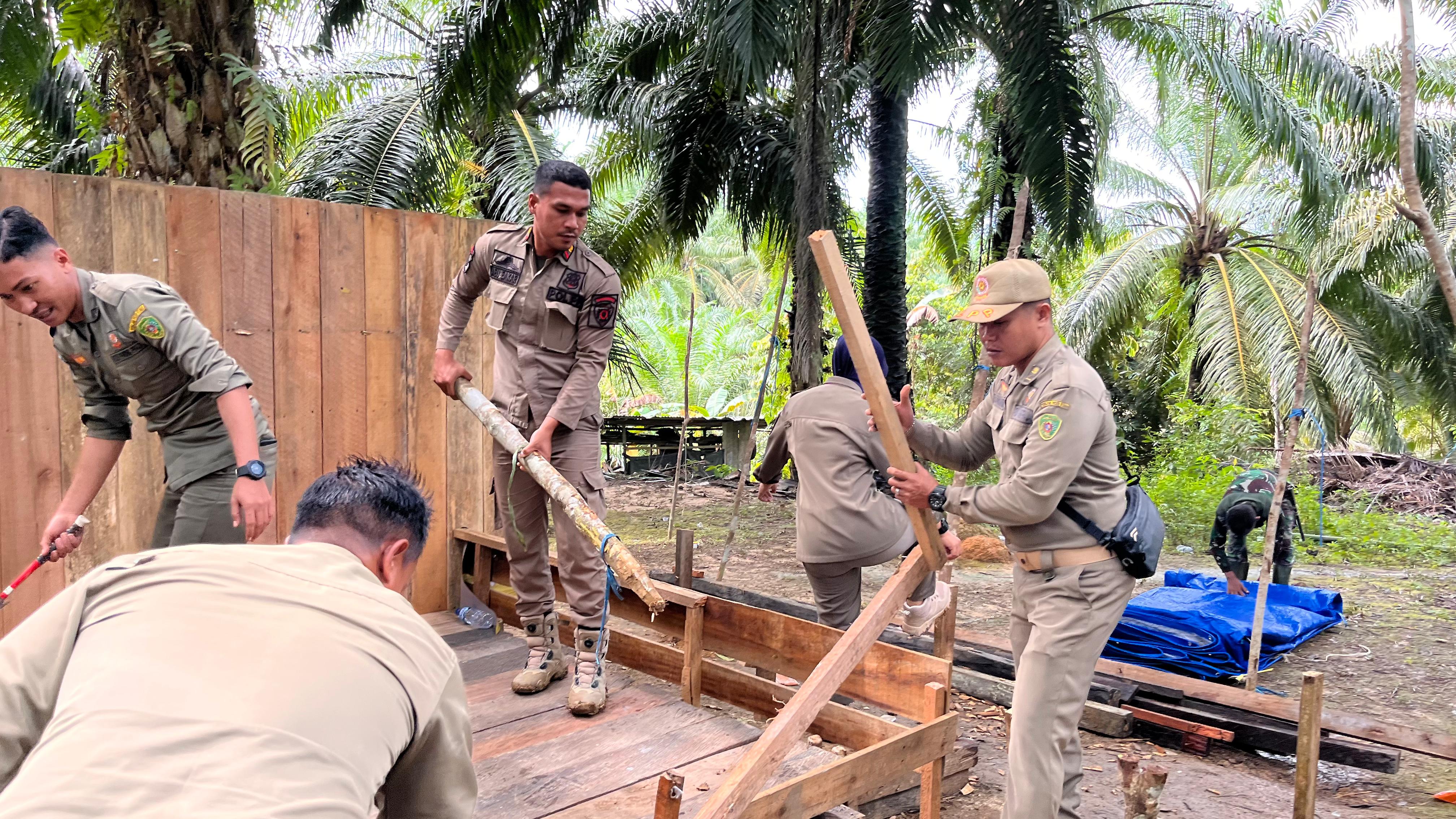 MERESAHKAN: Personel Satpol PP dan Kodim menghancurkan arena judi dadu dan sabung ayam yang meresahkan warga Buluminung. (DISKOMINFO PPU UNTUK BERAU POST)
