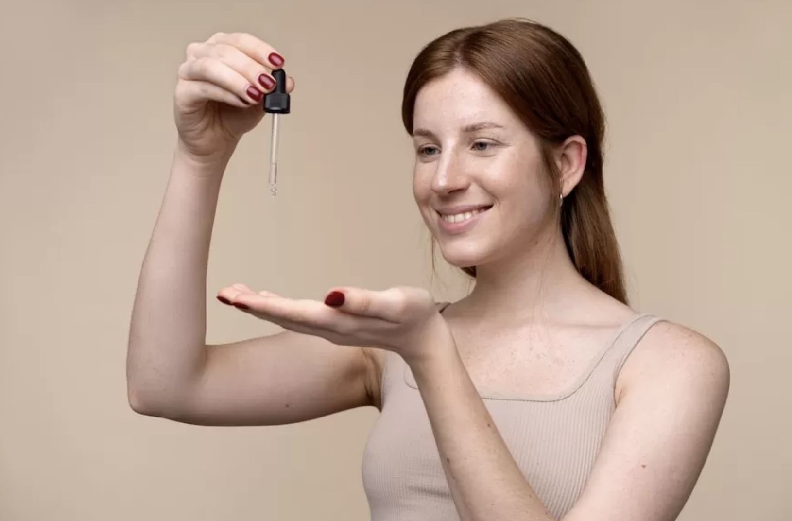 Tangan memegang botol serum dengan label bahan-bahan, menggambarkan perhatian terhadap komposisi produk perawatan kulit. (Freepik)