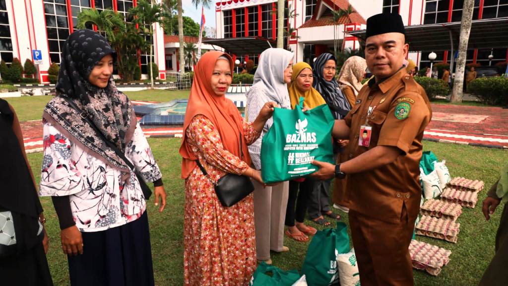DISERAHKAN: Asisten I Setkab Kukar Akhmad Taufik Hidayat menyerahkan zakat berupa bahan pangan pokok dari Unit Pengumpul Zakat Setkab Kukar kepada salah seorang mustahiq. (DISKOMINFO KUKAR UNTUK BP)