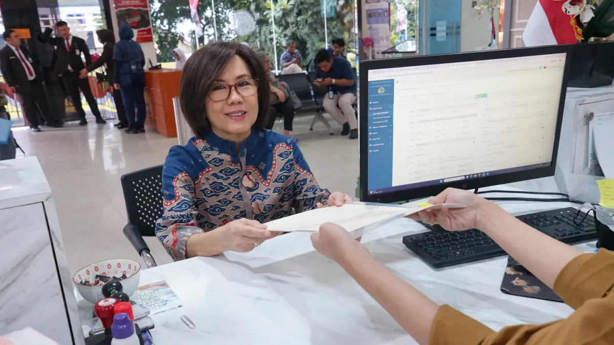 MANFAAT LAYANAN PERINTIS 10 HARI: Warga Jakarta Utara, Dewi Himjati, menunjukkan sertipikat tanah hasil pengurusan melalui program Peralihan Hak Terintegrasi (PERINTIS) 10 Hari di Kantah Kota Administrasi Jakarta Utara.