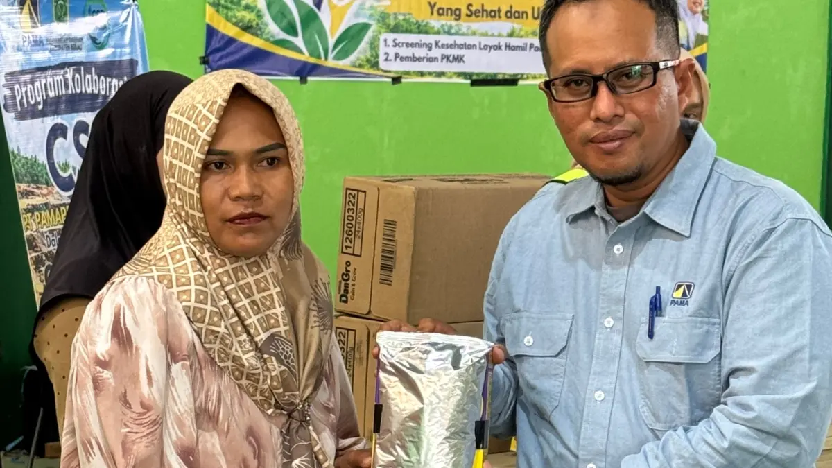 KOMITMEN: Deputi Project Manager PAMA, Kushartanto, memberikan susu PKMK kepada salah satu warga Gurimbang. (PAMA UNTUK BERAU POST)
